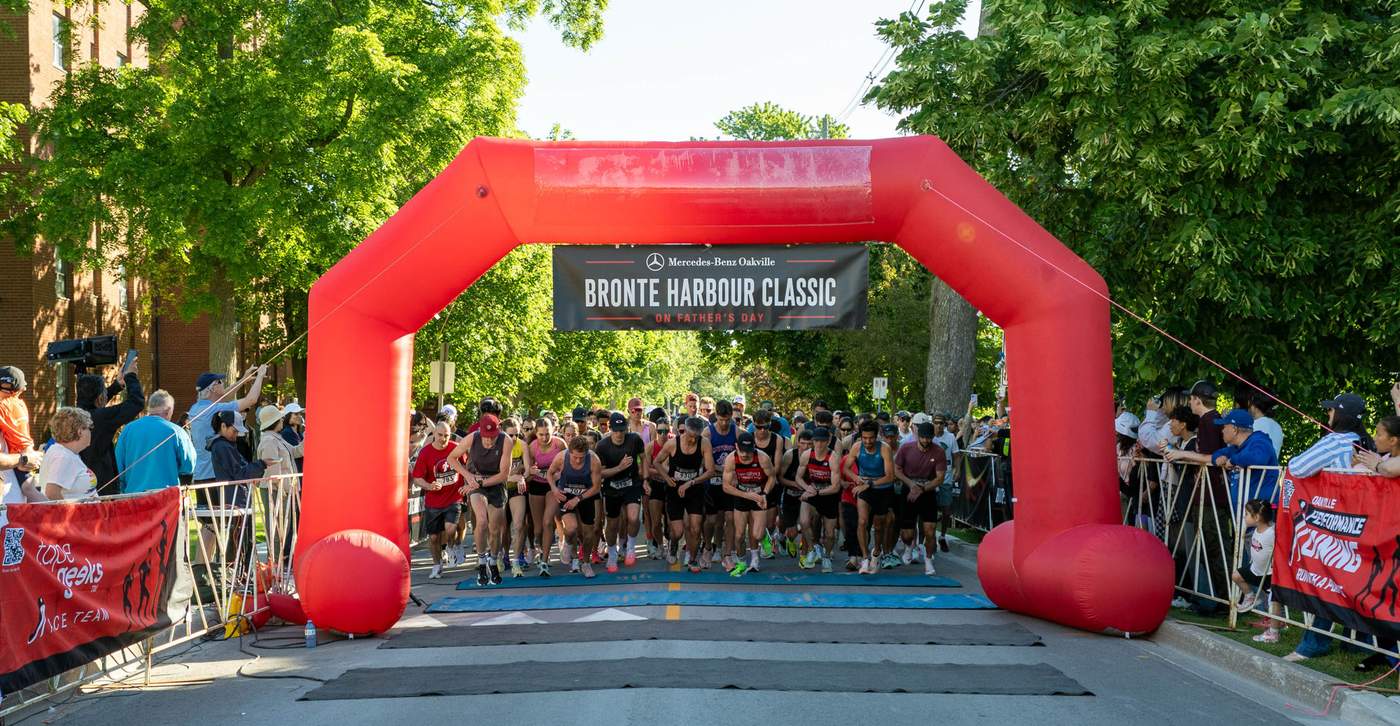 800+ runners launching under the red Mercedes-Benz Oakville arch at the start of the Bronte Harbour Classic 5K, Bronte Heritage Waterfront Park, Oakville