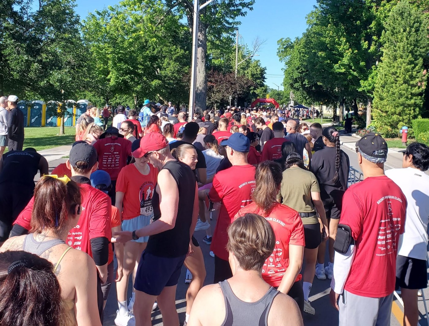 Hundreds of runners in red race shirts packed into the start corral of the Mercedes-Benz Oakville Bronte Harbour Classic 5K in Oakville
