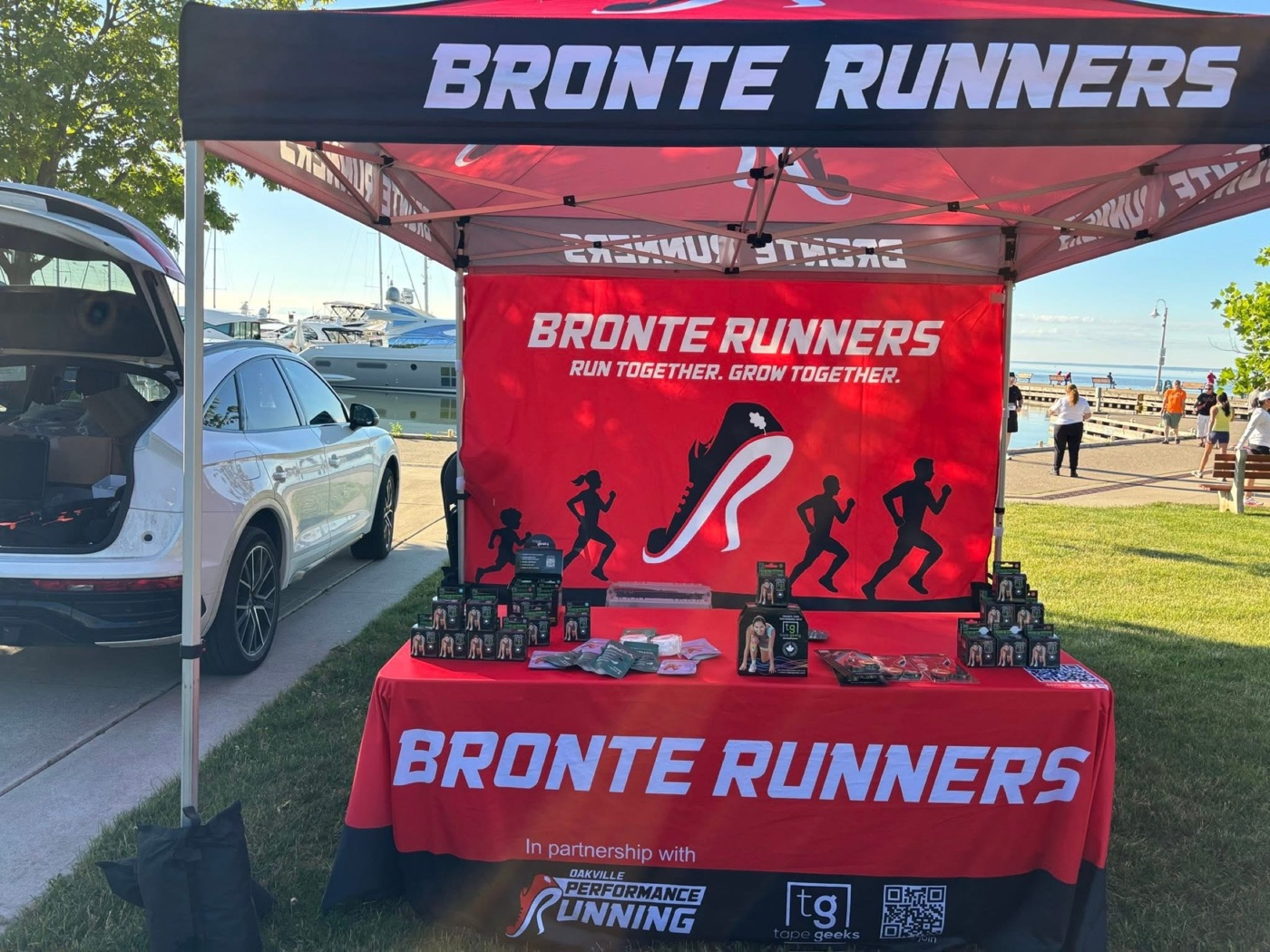 The Bronte Runners tent at the Mercedes-Benz Oakville Bronte Harbour Classic 5K festival, stocked with TapeGeeks kinesiology tape beside the harbour at Bronte Heritage Waterfront Park, Oakville